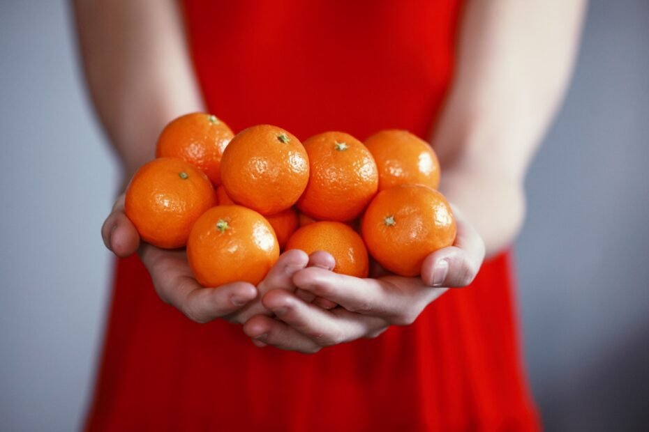 Person in red dress offering tangerines